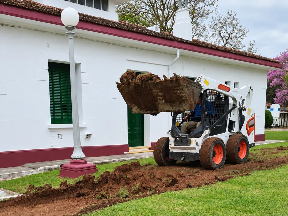 Minicargadora Bobcat abriendo una zanja junto a un edificio